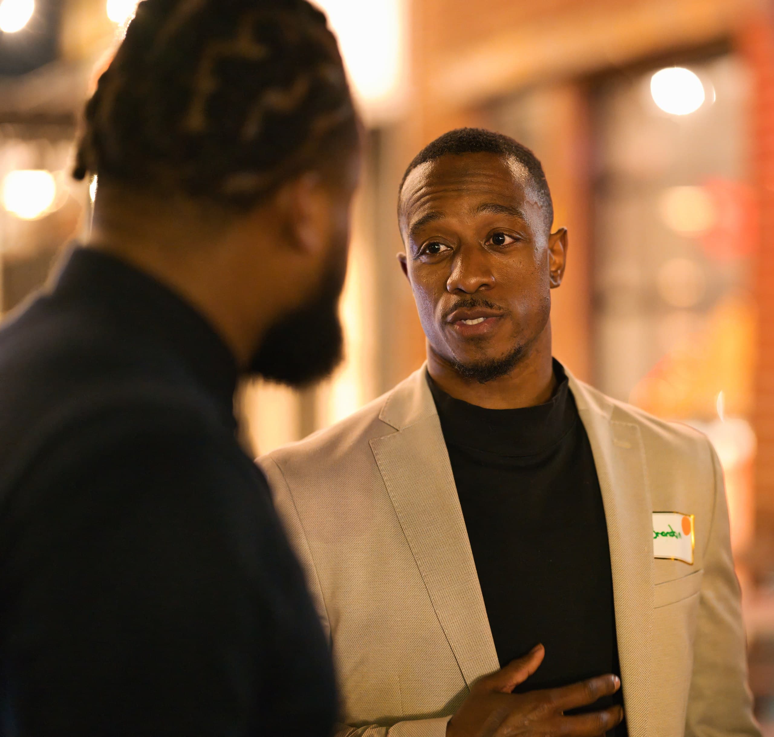 Guest in a tan blazer in conversation at an evening event
