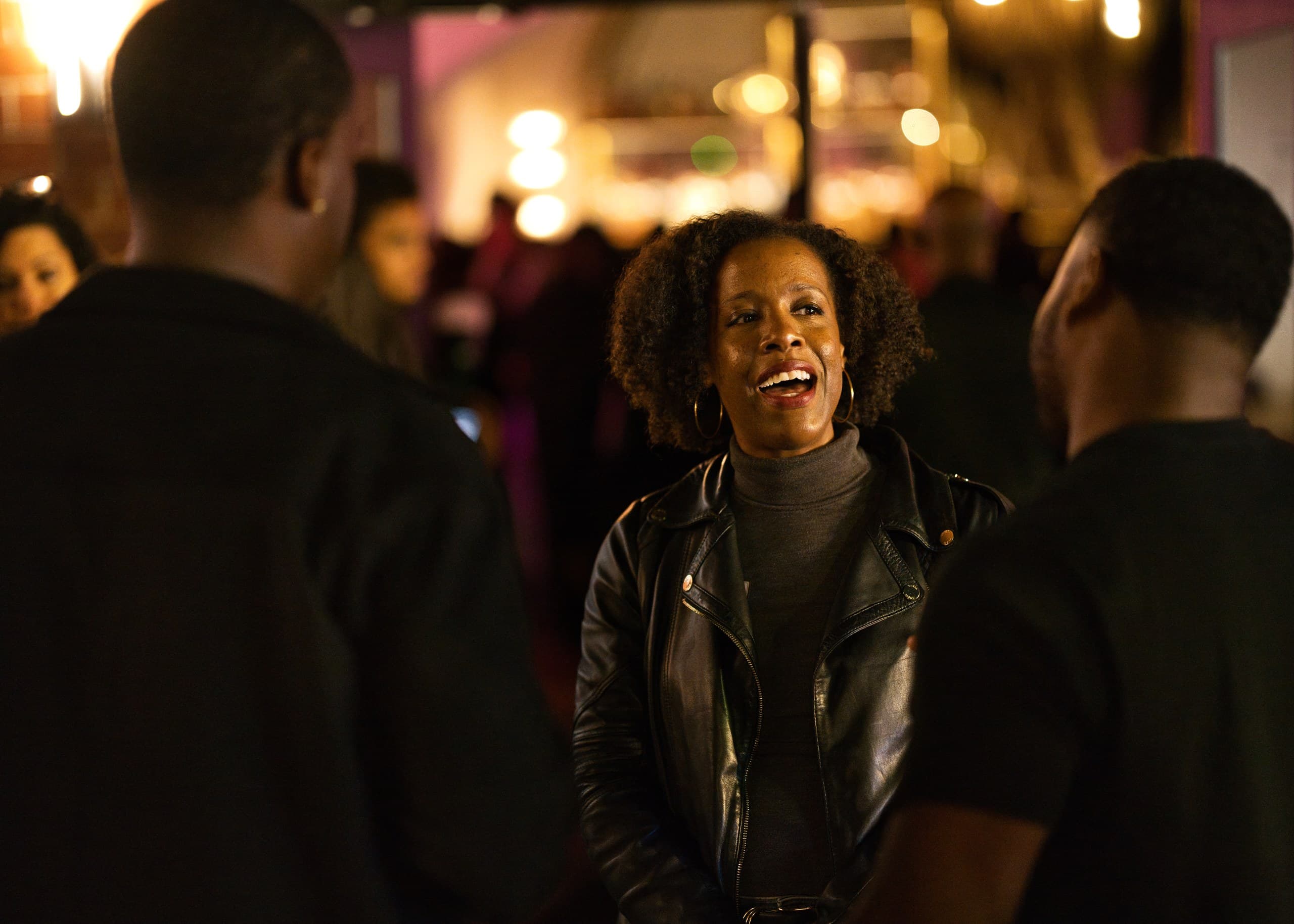 Guest in a leather jacket laughing with friends at a night event