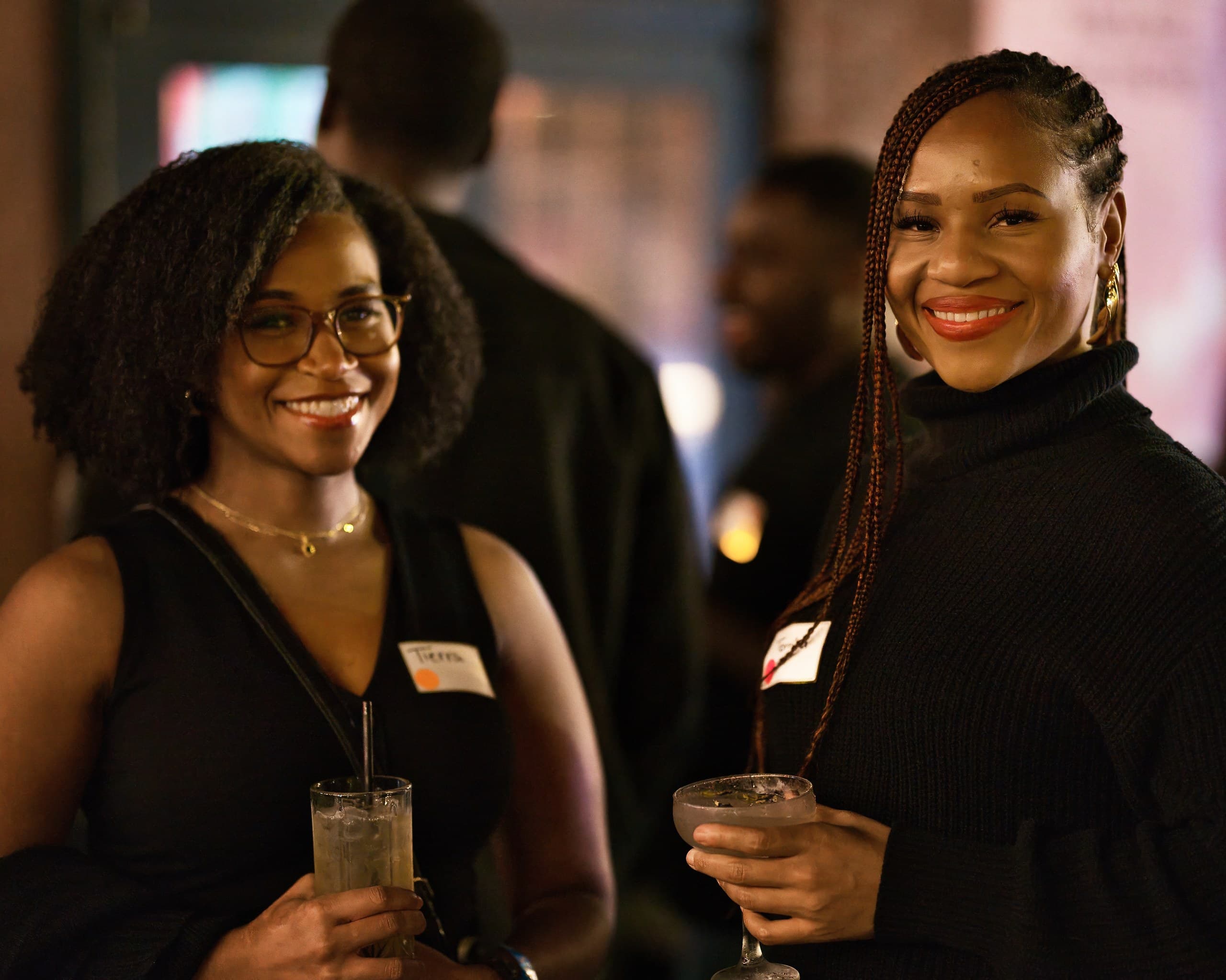 Two guests holding cocktails and smiling at an evening reception