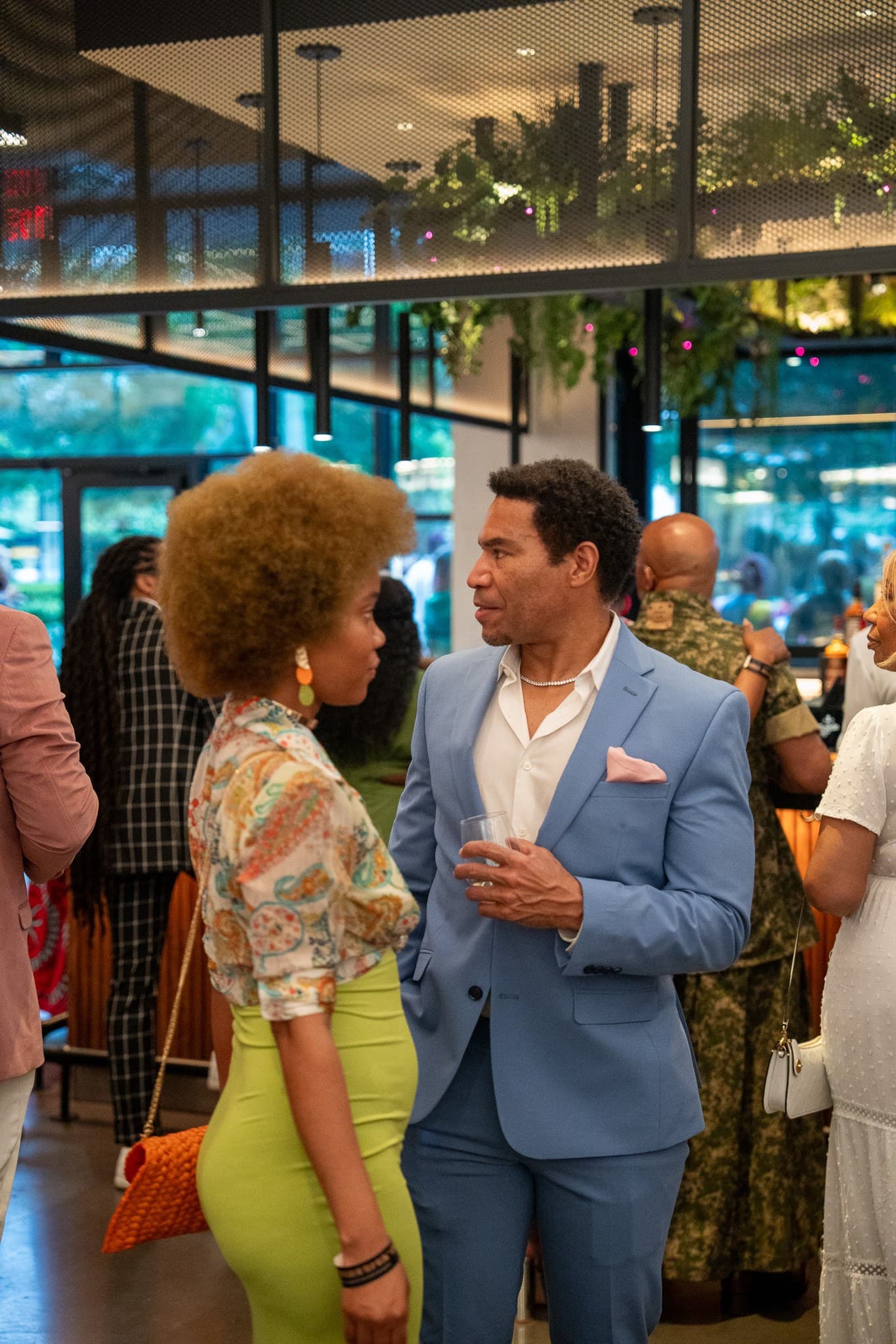 Two guests in conversation at a crowded indoor reception