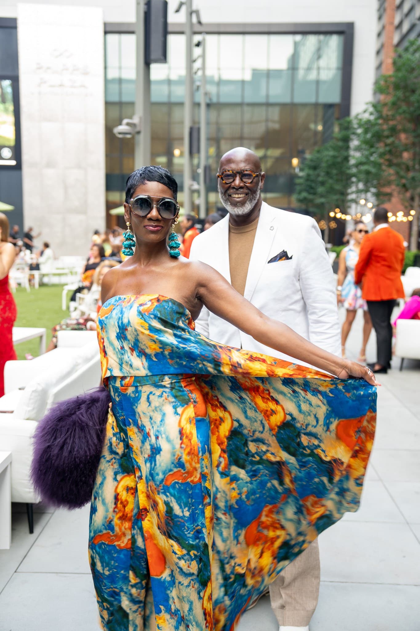 Guest in a flowing printed gown twirling on an outdoor plaza at a summer event
