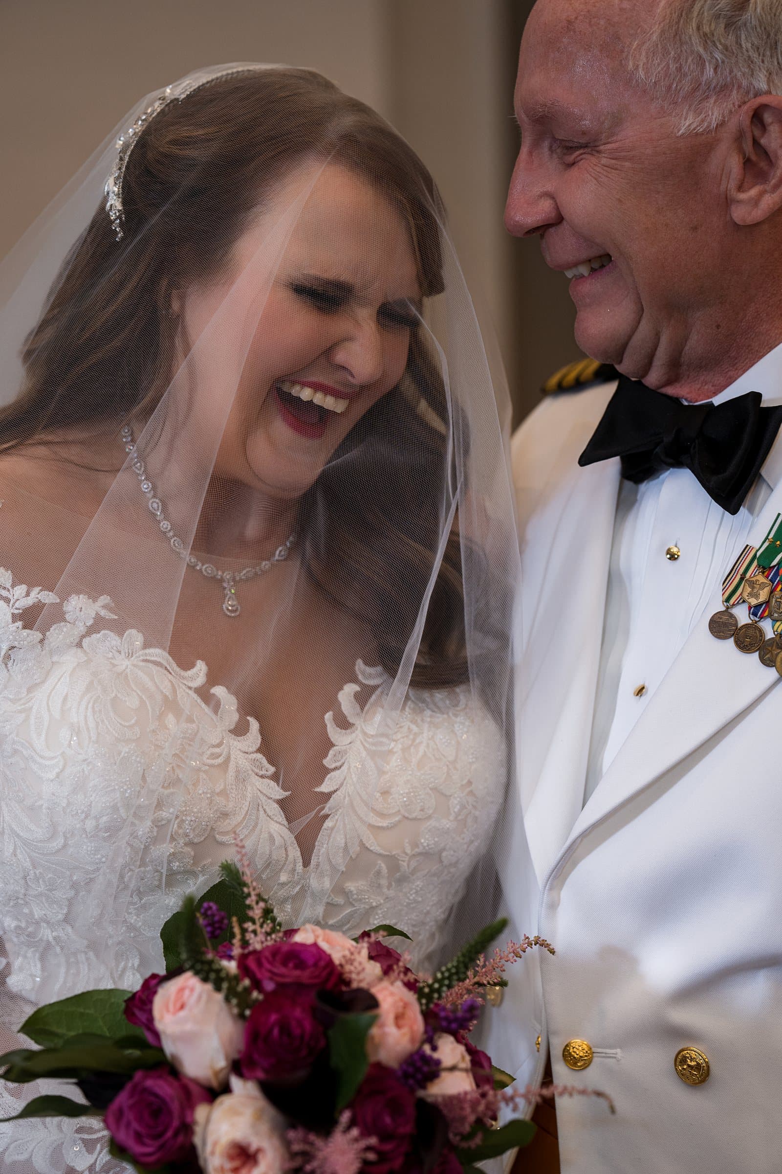 Kimberly laughing beside Robert, her bouquet of burgundy and blush roses