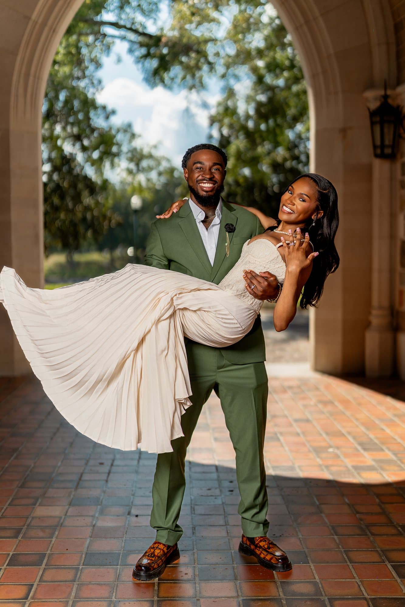 The groom carrying the bride beneath the arches at Berry College